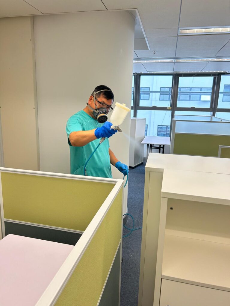 穿著防護裝備的工作人員在辦公室內使用噴槍進行除甲醛作業
